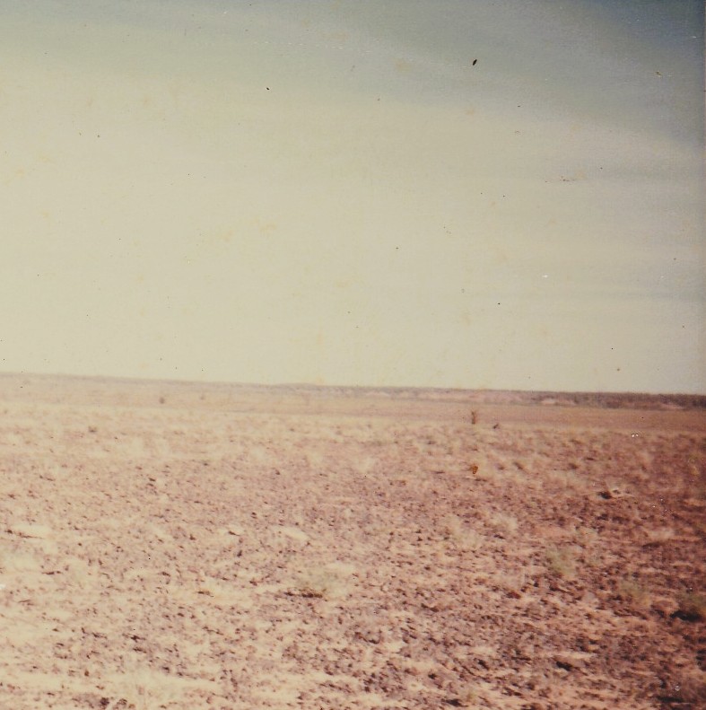 An empty flat outback landscape. Dried earth - Hot sky. There is nothing else.